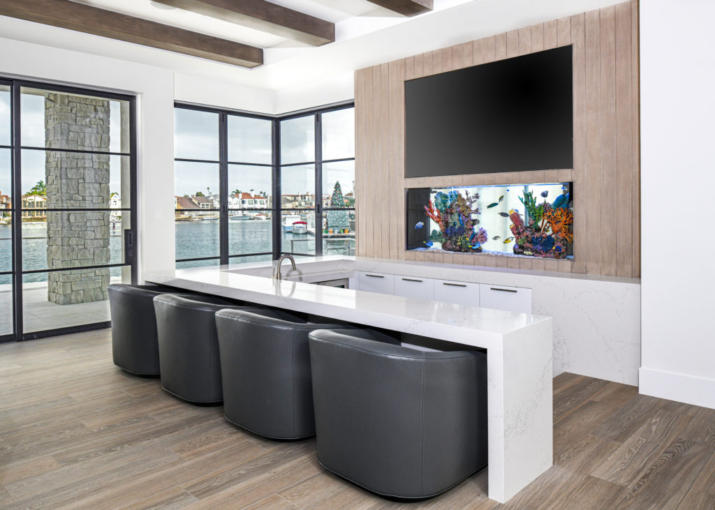 Aquarium inside wall in behind a wet bar with four chairs and a view